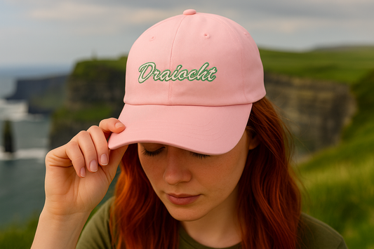 Pink cdad cap embroidered with 'Draíocht' in white and Kelly green, worn for stylish Irish adventures.
