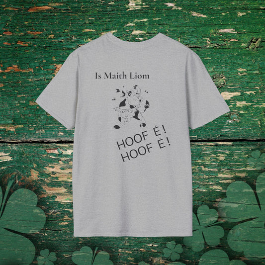 Unisex Grey t-shirt with Gaeilge phrase “Is Maith Liom HOOF É” and dancing cow illustration, playful heritage humor design on a green, distressed fence